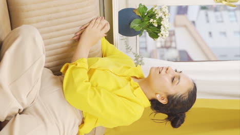 Vertical-video-of-Happy-and-peaceful-young-woman.-She-is-sitting-in-front-of-the-window.